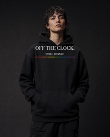 FÆBRIQ Off The Clock. Still Iconic. Heavyweight Hoodie — three-quarter on-model view showing the white chest print and six-stripe Pride Circuit bar.